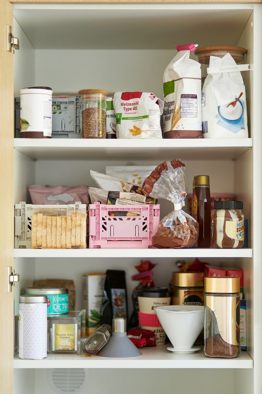 A middle-aged woman tidies up her cupboard in the kitchen and reorganizes everything to make a comparison before and after